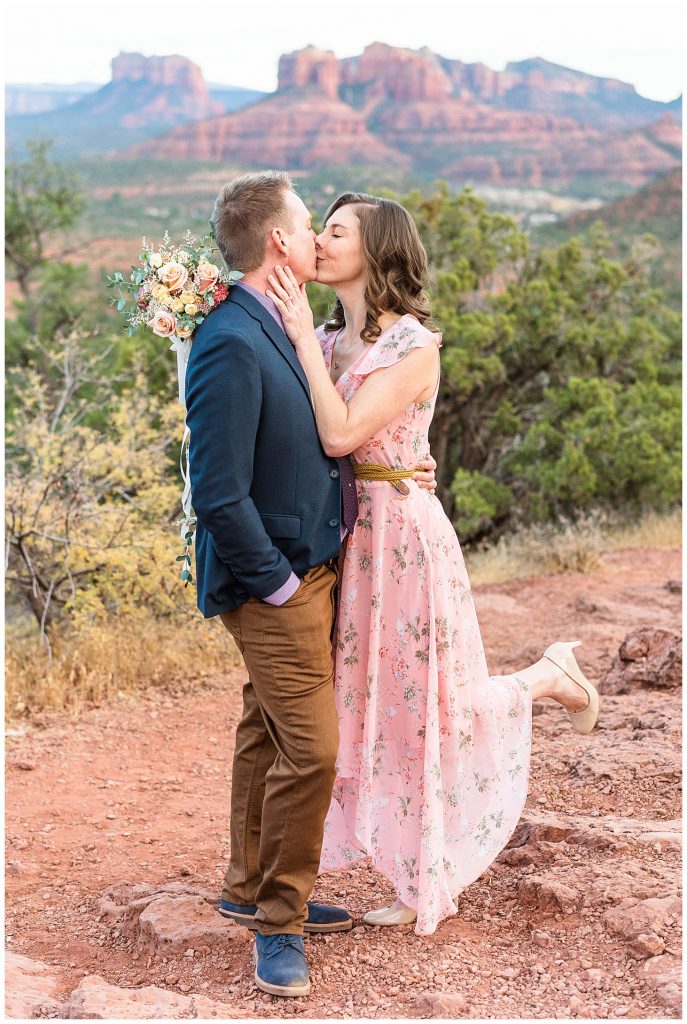 Couple kissing with flower bouquet after getting engaged in Sedona, Arizona