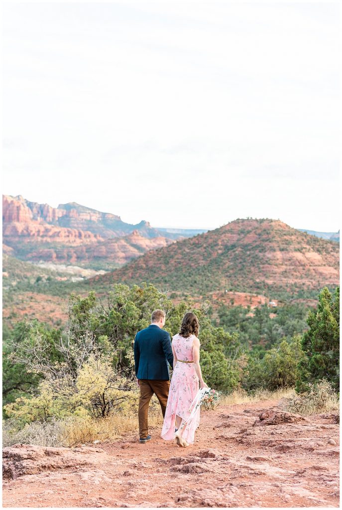 Couple walking along cliff edge after getting engaged in Sedona, Arizona