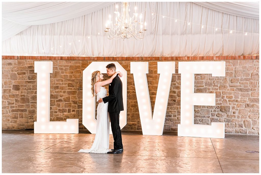 Bride and groom in front of love marquee letters at Stonebridge Manor wedding venue in Mesa, Arizona