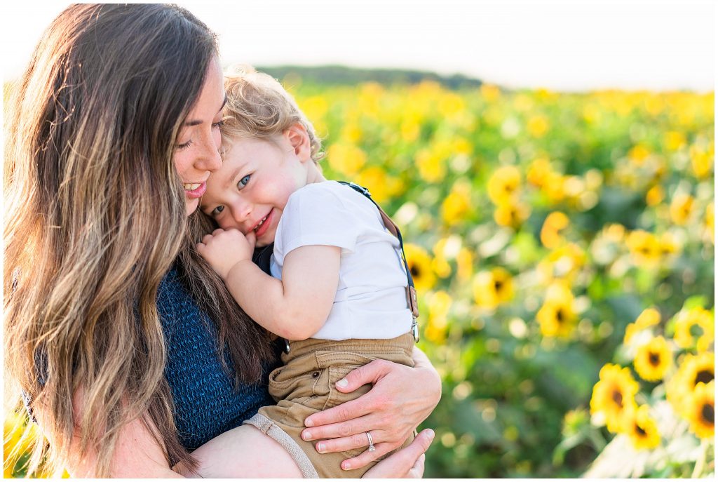 mom hugging little boy in sunflower field